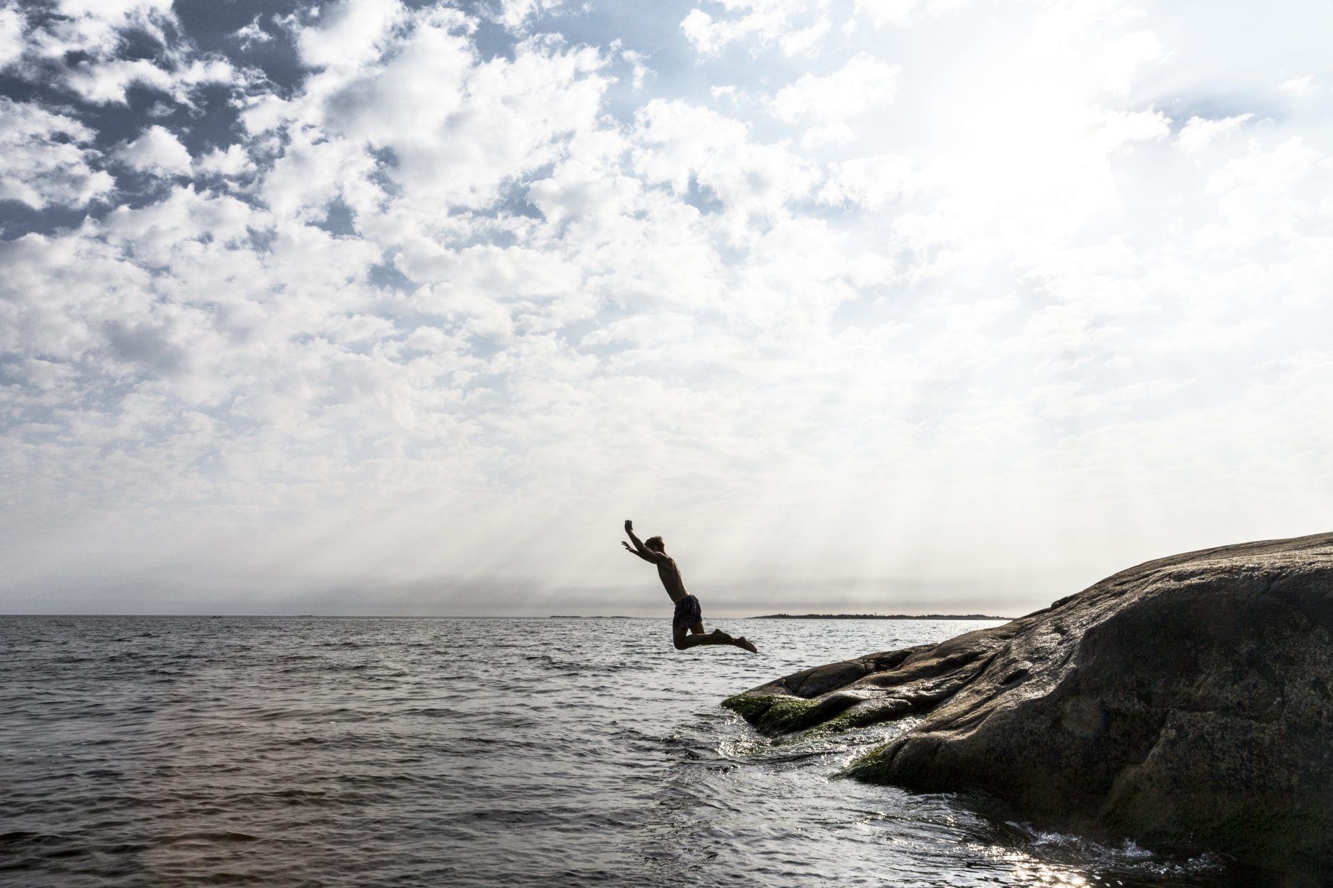 Person hoppar i havet från klippa.