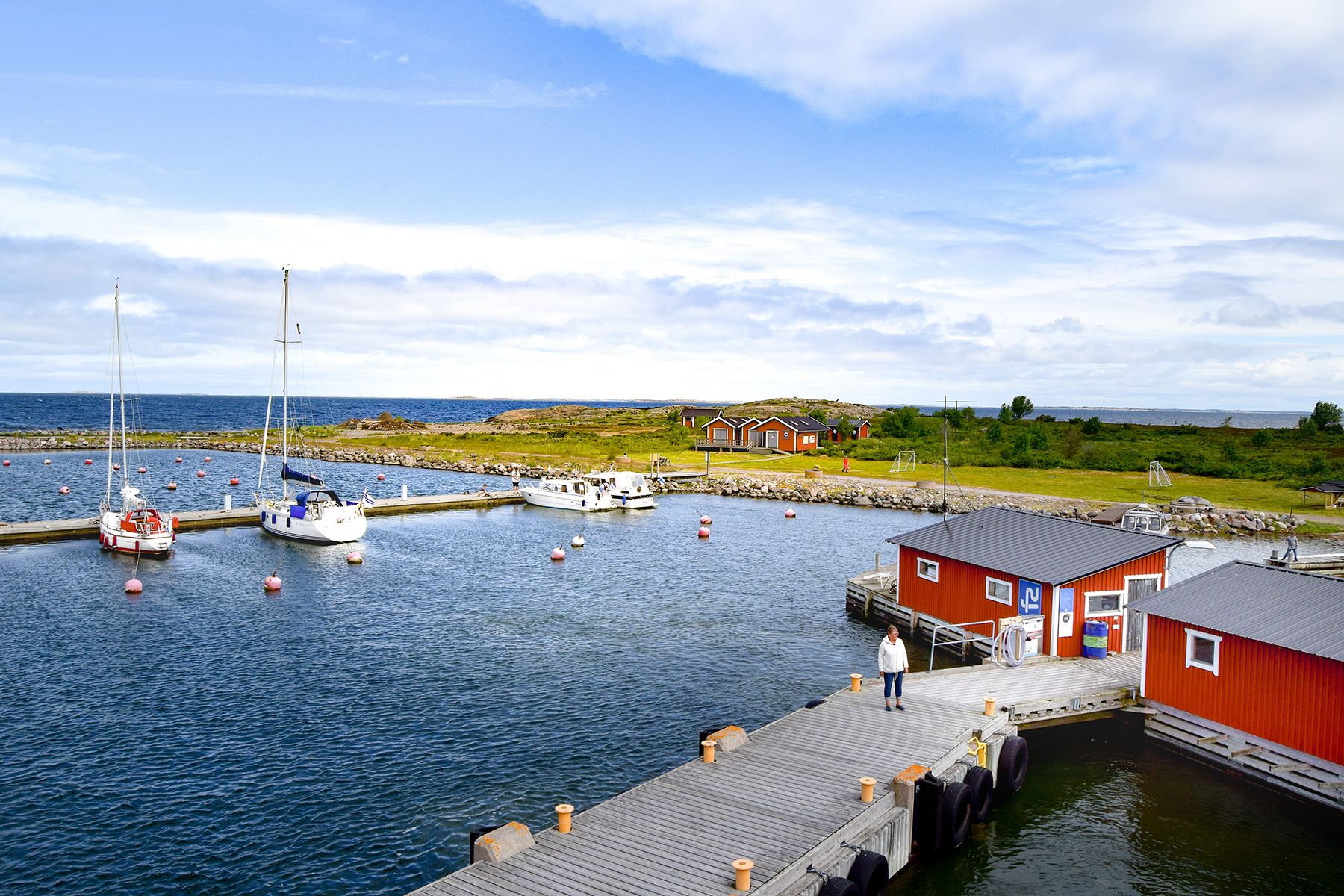 The harbour on the island of Jurmo, featuring red wooden buildings and sailboats.
