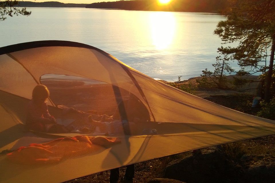 A person looks out at the setting sun from inside a tentsile tent at Ruissalo Spa & Hotel.