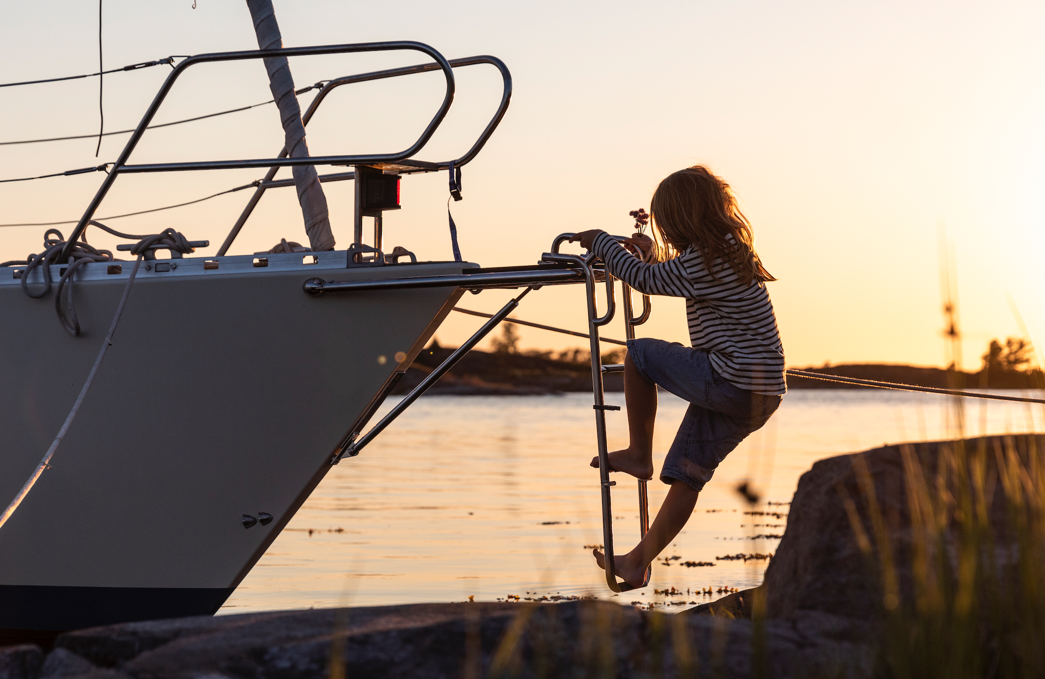 Flicka klättrar segelbåt skymning.