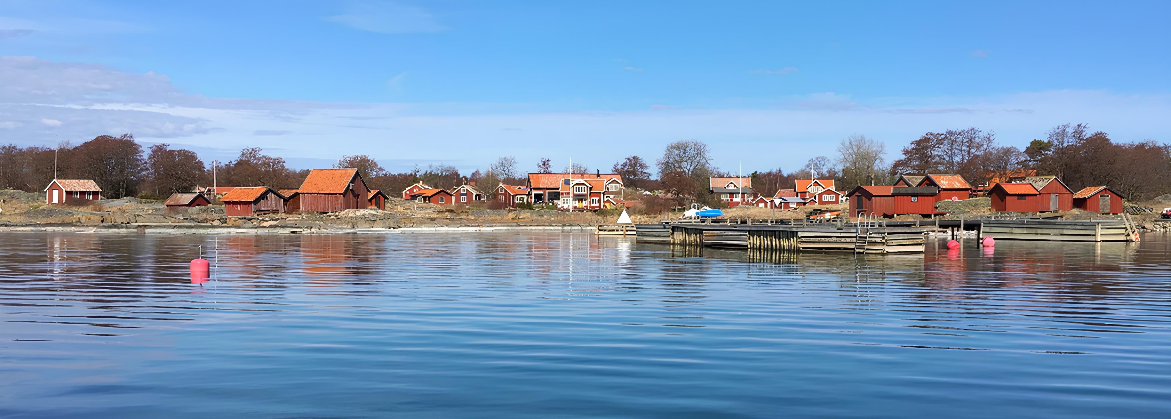 Blank vattenspegel med en kustlinje i bakgrunden.