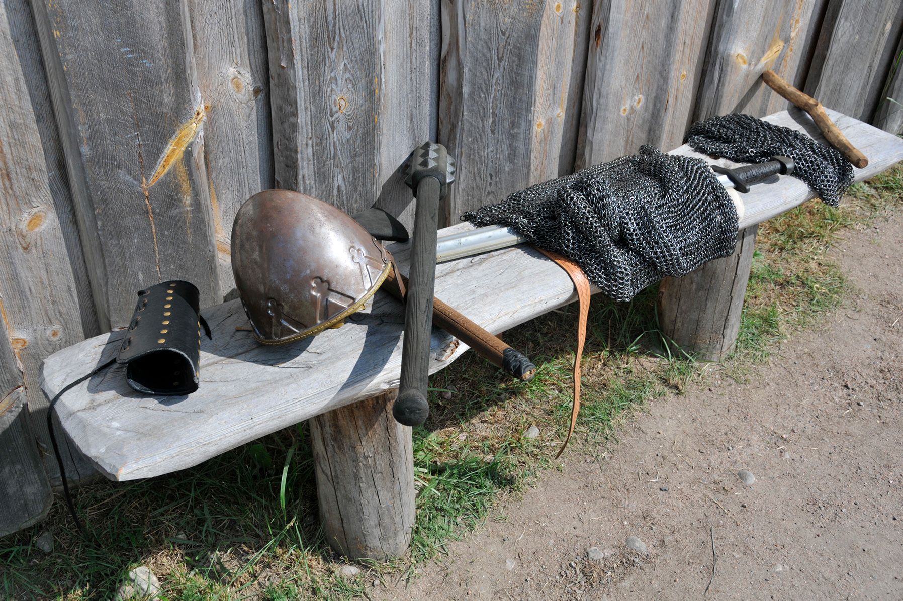 Bronze Viking helmets on a wooden bench along with a metal chest plate and sword.